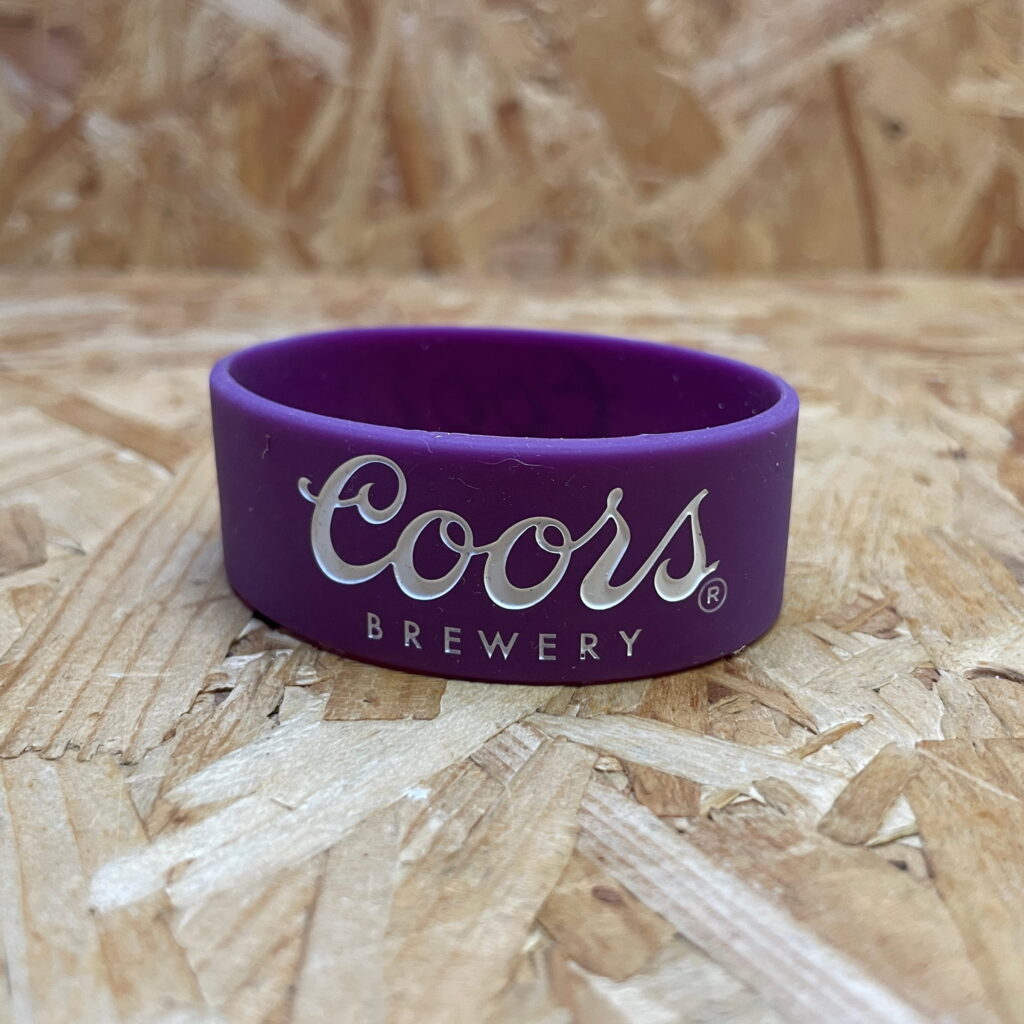 A purple debossed silicone wristband with white ink-fill displaying the "Coors Brewery" logo.